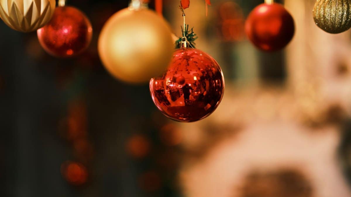 Close-up of shiny red and gold Christmas ornaments hanging indoors, capturing festive holiday spirit.