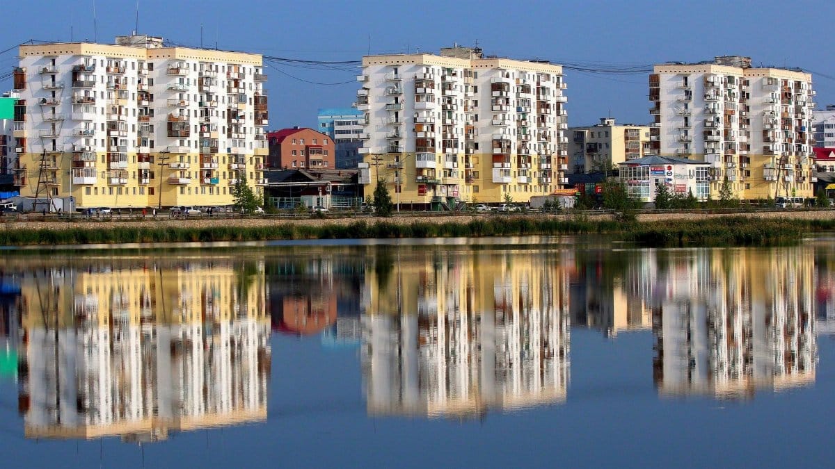 Modern apartment buildings with serene reflections in a city waterfront setting.