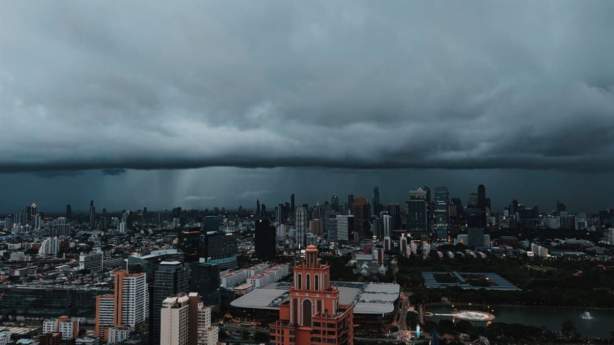 Aerial view of Bangkok's urban skyline under dark storm clouds, capturing the city's dramatic atmosphere.