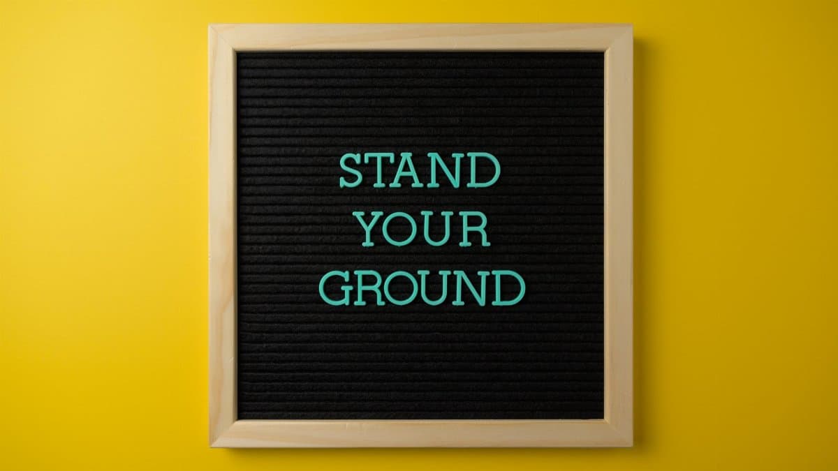 Motivational message 'Stand Your Ground' on a letter board against a yellow backdrop.