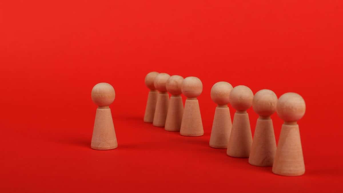 Group of wooden figurines arranged on a bold red background symbolizing leadership and teamwork.