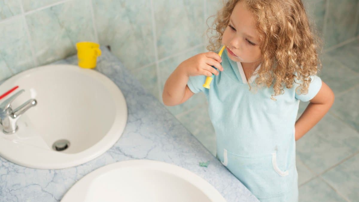 Child brushing teeth by sink, highlighting personal hygiene habits.
