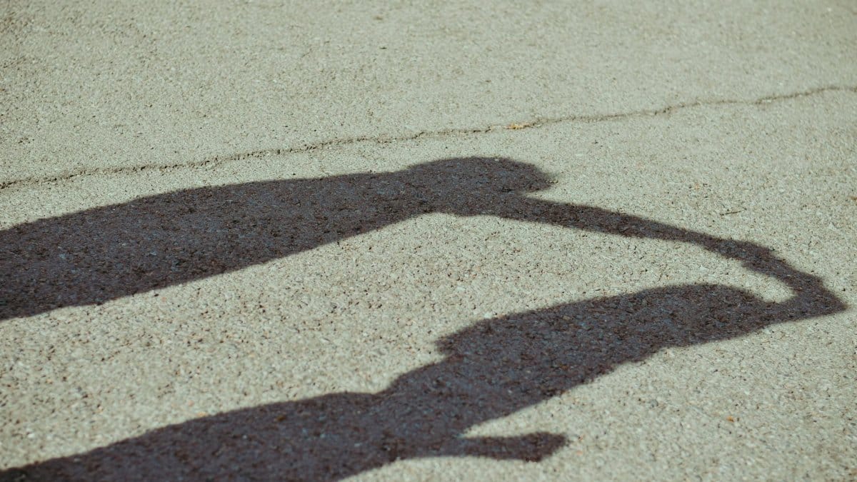 Shadow of two people holding hands on pavement, representing connection and companionship.