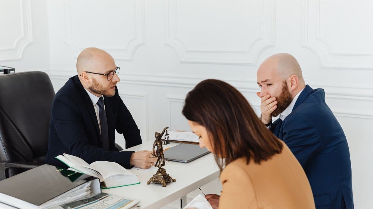 A serious legal consultation in a professional office environment involving three adults.