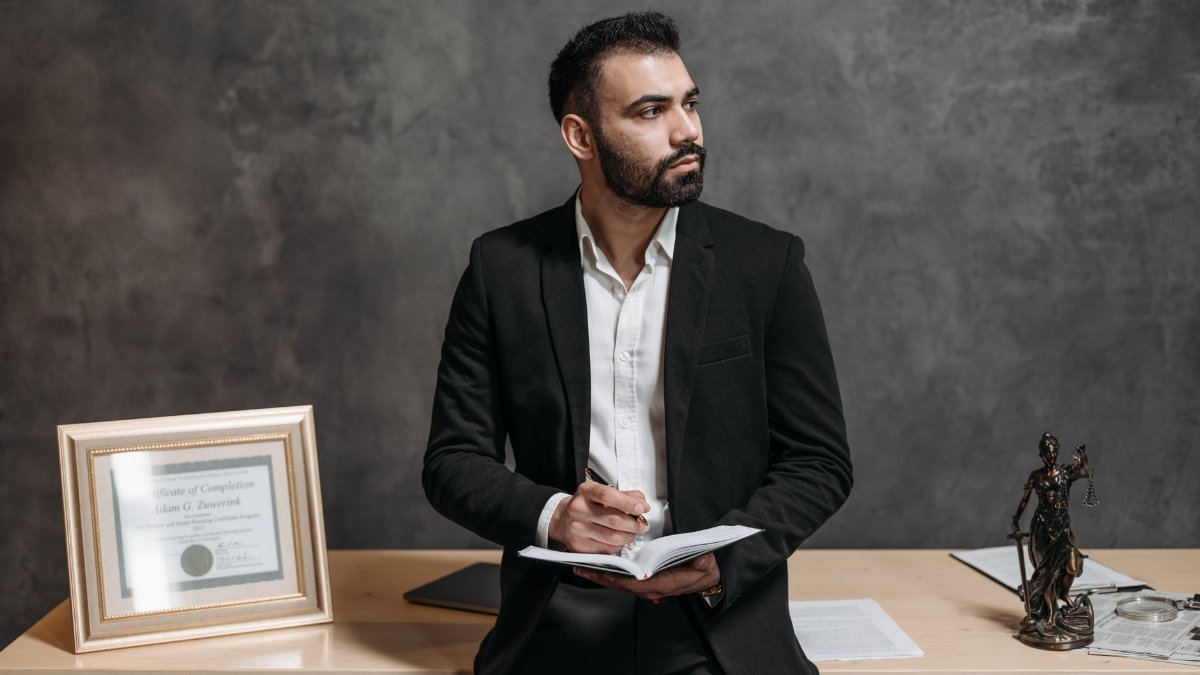 Confident male consultant takes notes, surrounded by legal paperwork in a modern office.