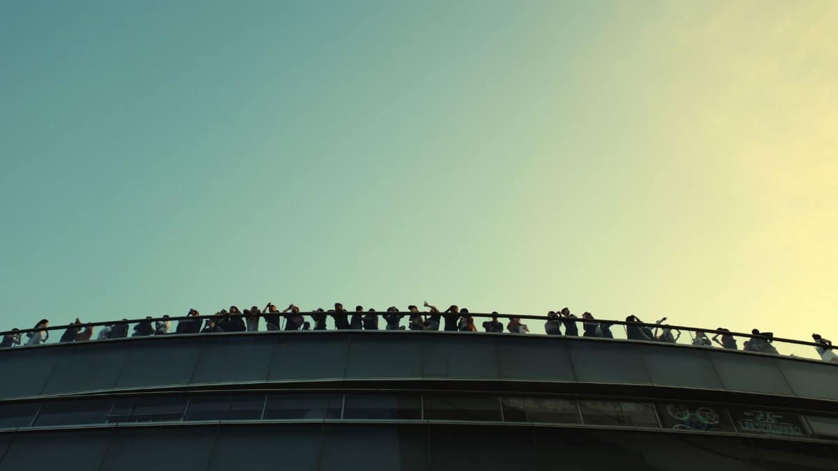 Dramatic silhouettes of people enjoying a glass walkway view in Hong Kong against the sunset.