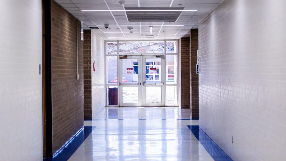 Wide and bright school hallway with glass exit doors leading outside, creating a welcoming atmosphere.