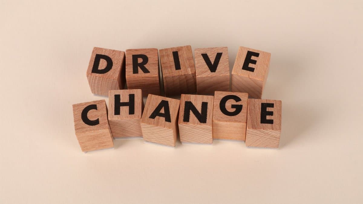 Wooden blocks spelling 'Drive Change' on a neutral background, symbolizing motivation and growth.