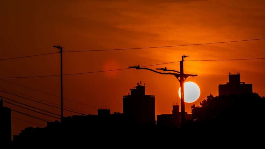 Stunning silhouette of city buildings against a red sunset sky with power lines.