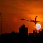 Stunning silhouette of city buildings against a red sunset sky with power lines.