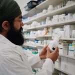 Pharmacist with turban organizing shelves in a pharmacy, focused on healthcare.