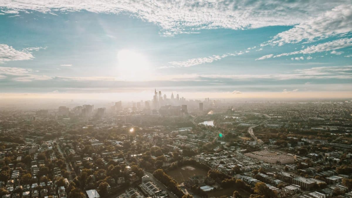 Stunning aerial view of Philadelphia cityscape with the sun rising over the horizon, highlighting the urban landscape.