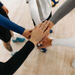 Close-up of athletes joining hands in a motivational sports huddle on an indoor court.