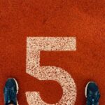 Runner's feet on track lane 5 at the finish line, symbolizing completion and success.
