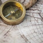 A vintage brass compass rests on an antique map with a nautical rope, evoking exploration and discovery.