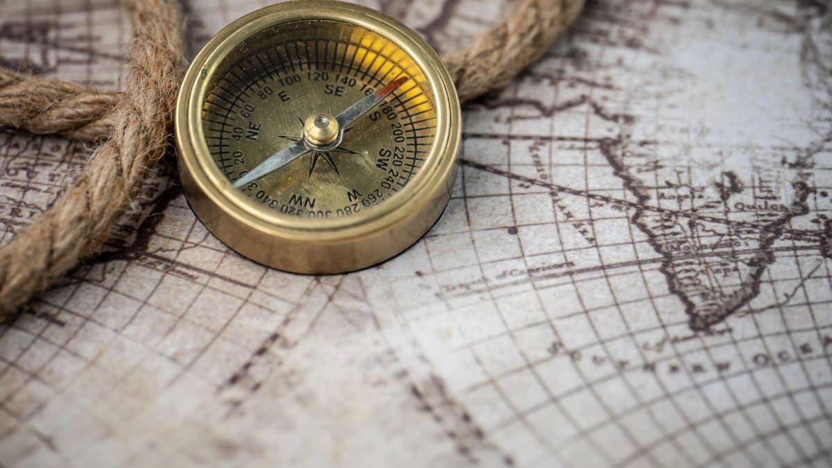 A vintage brass compass rests on an antique map with a nautical rope, evoking exploration and discovery.