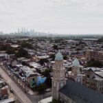 Aerial view showcasing Philadelphia's skyline and urban landscape with a historic church in the foreground.