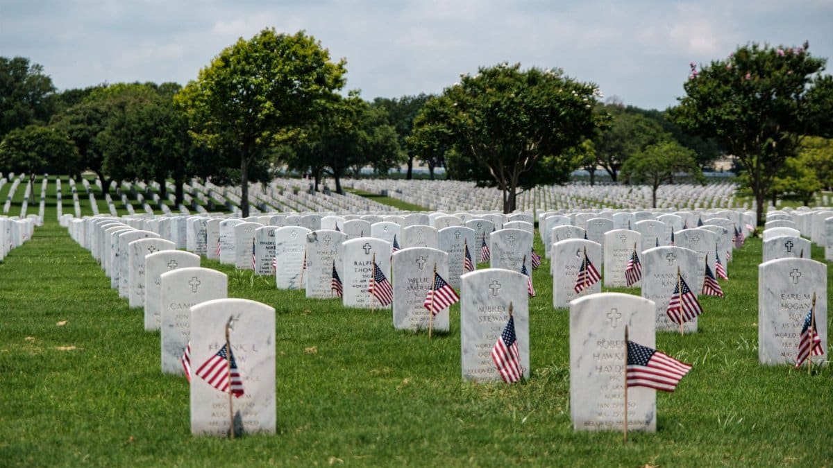 Gravestones with American flags at Fort Sam Houston National Cemetery, honoring Memorial Day.