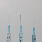 Close-up image of three syringes with needles against a neutral background.