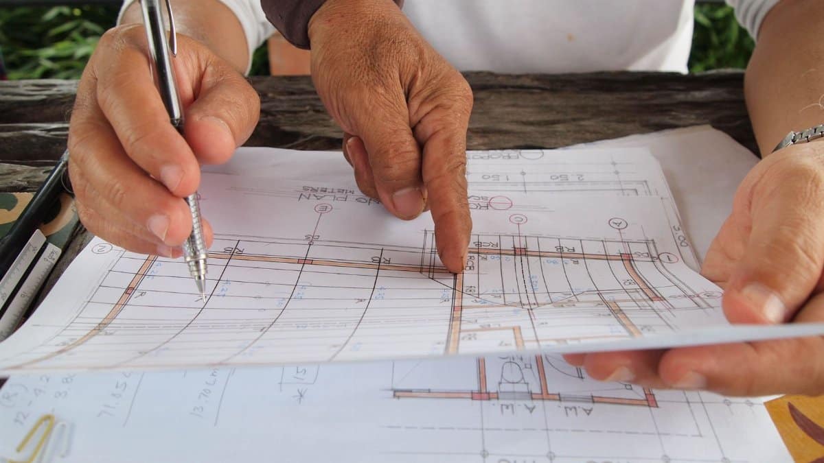 Two architects reviewing and discussing detailed blueprints at a workspace.