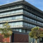 A contemporary office building featuring a striking glass facade and lush surroundings.