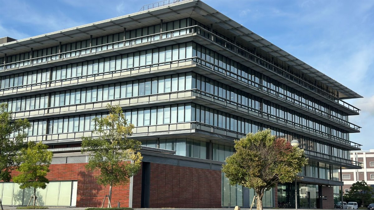 A contemporary office building featuring a striking glass facade and lush surroundings.