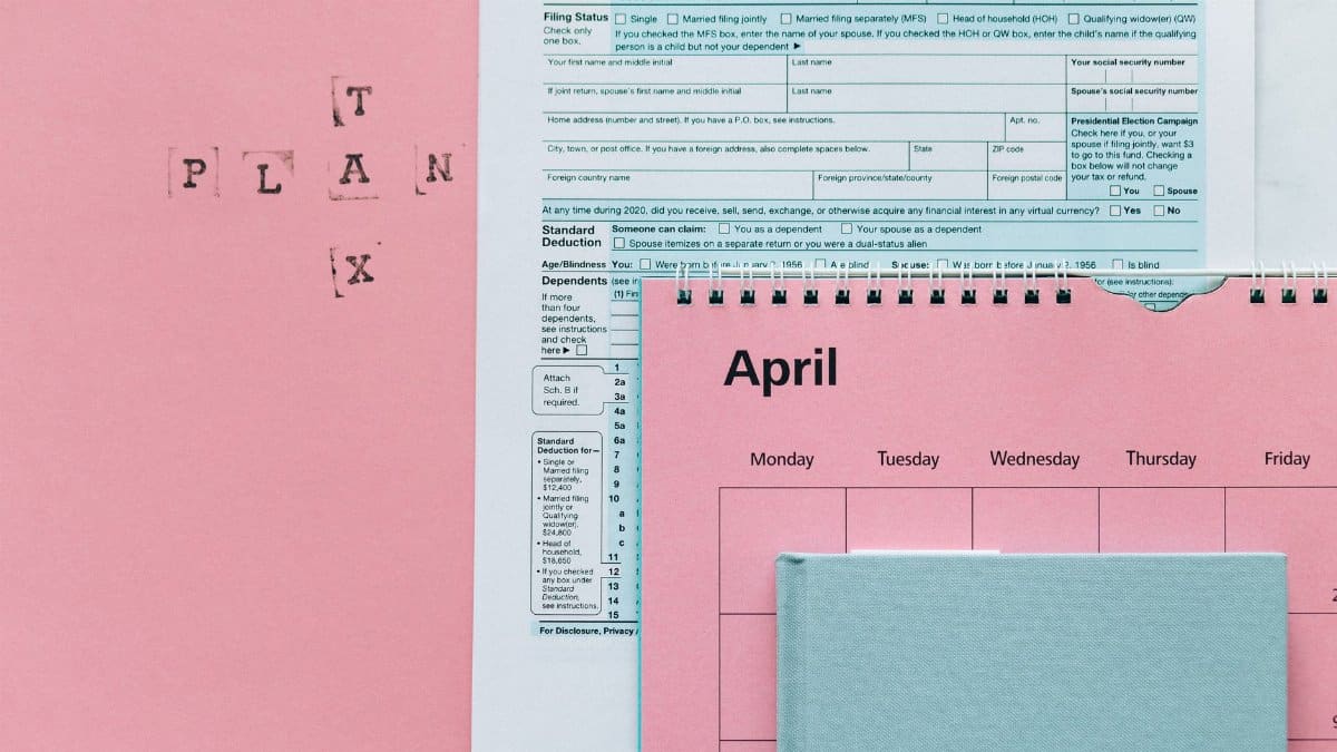 Tax-related items on a pink background, including forms and a calendar.