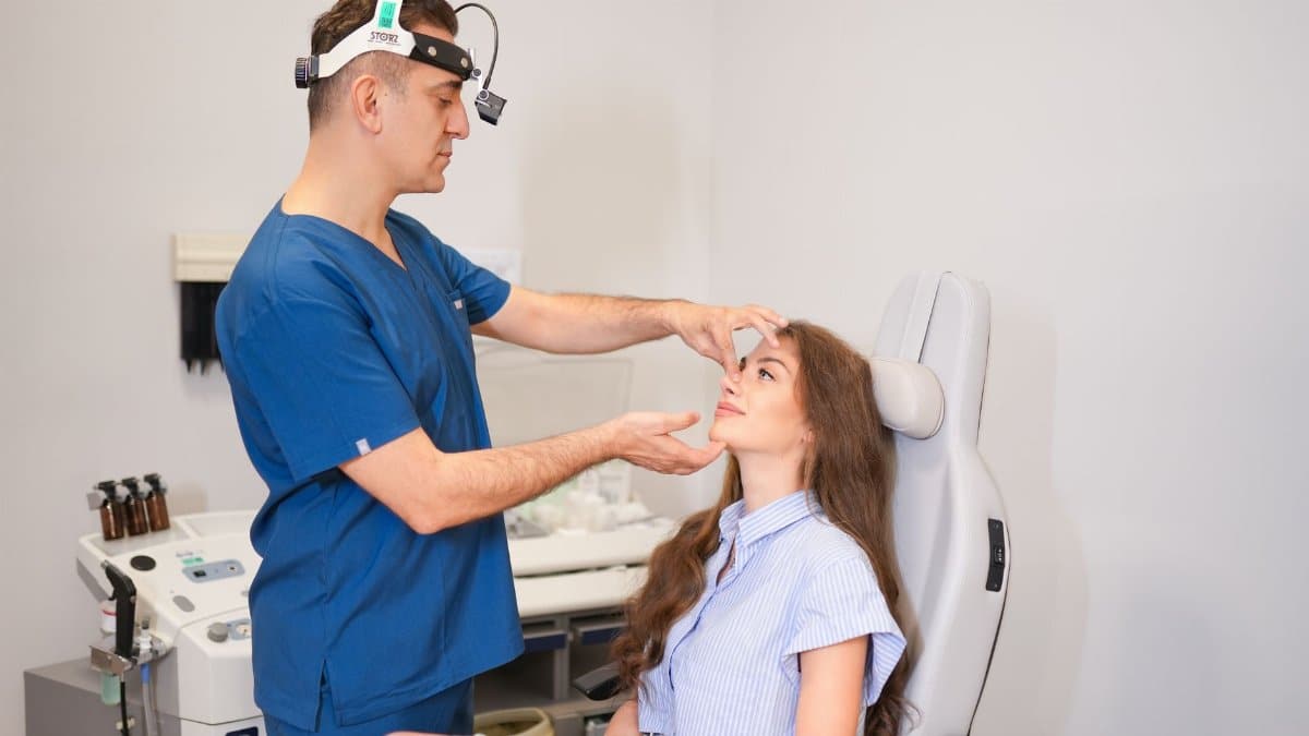 A plastic surgeon examines a patient's nose in a modern clinic setting in Istanbul.