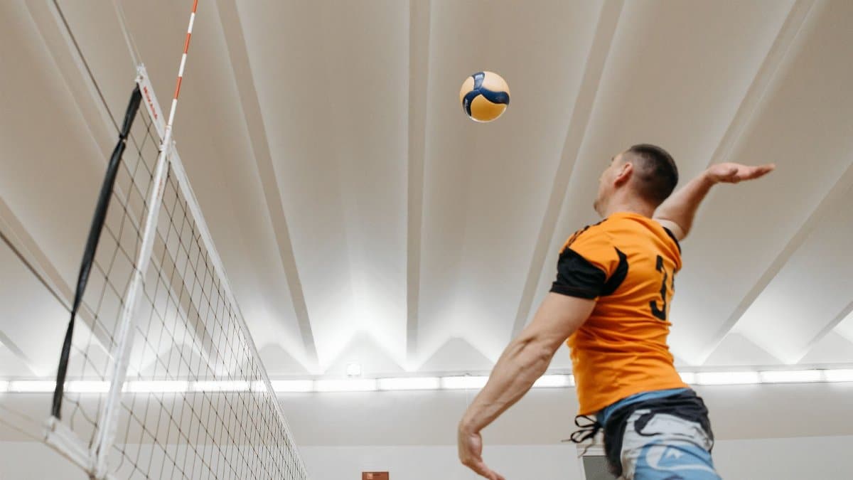Dynamic shot of a male volleyball player spiking the ball during an indoor match.