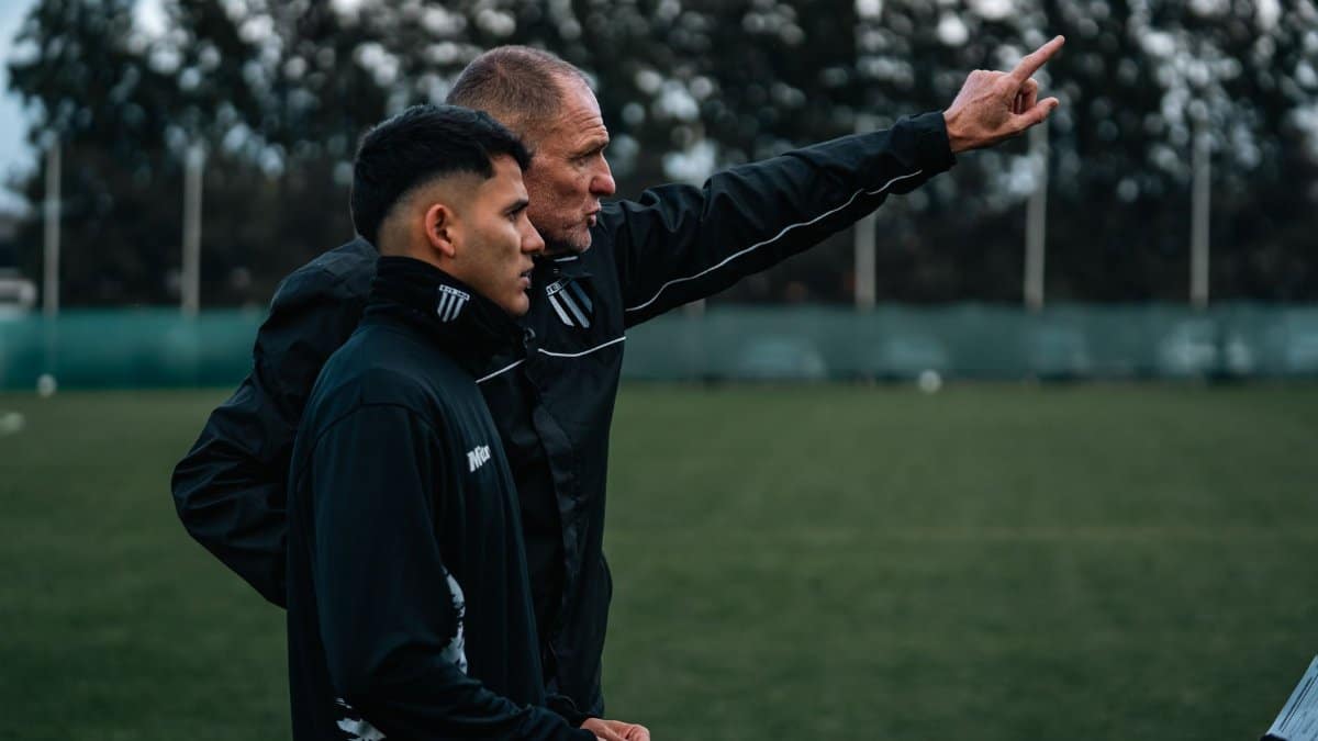 A soccer coach discusses strategy with a young player during outdoor training.
