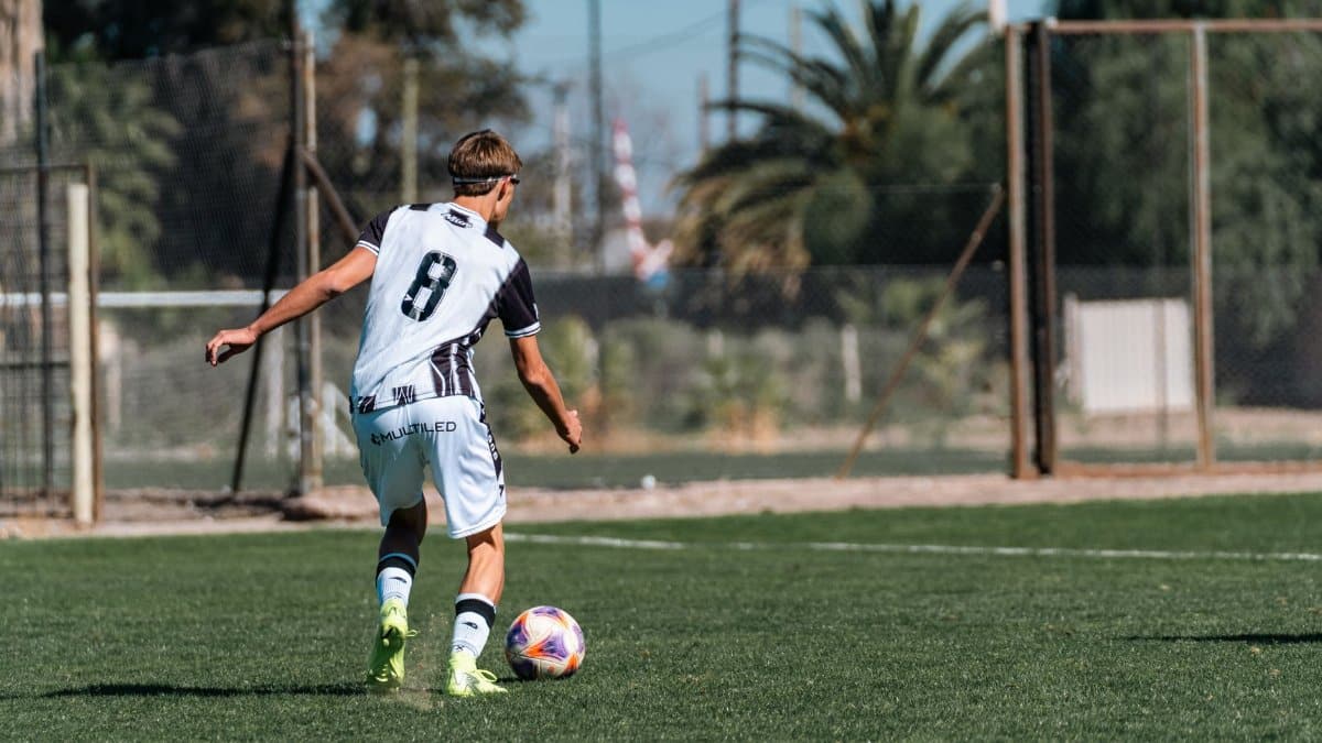A young soccer player in action, dribbling on an outdoor field during a sunny day.