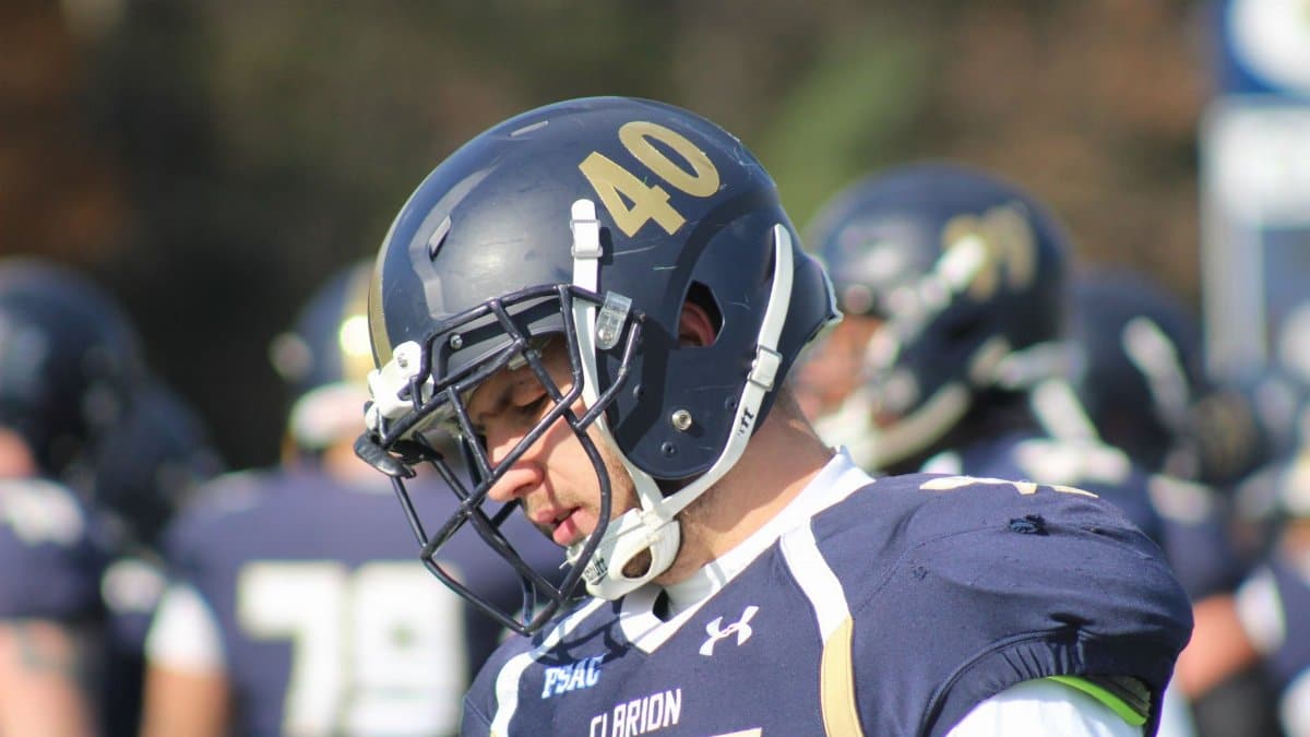 Football player in helmet and uniform focused during outdoor game.