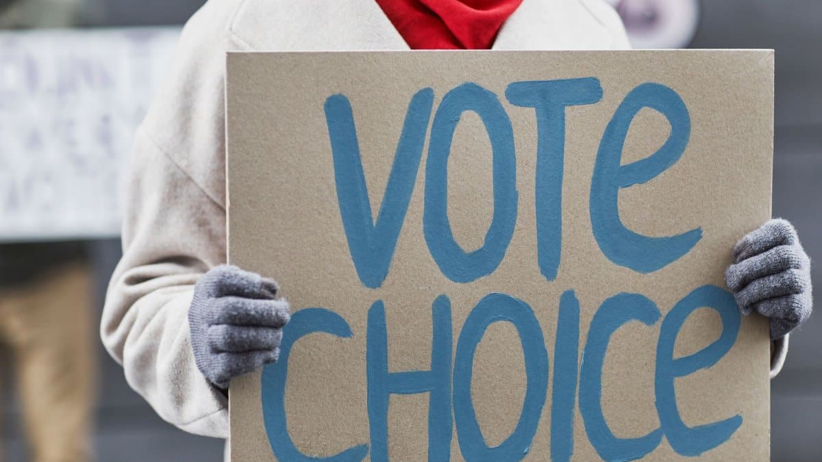 Close-up of a person holding a Vote Choice sign during a protest outdoors.