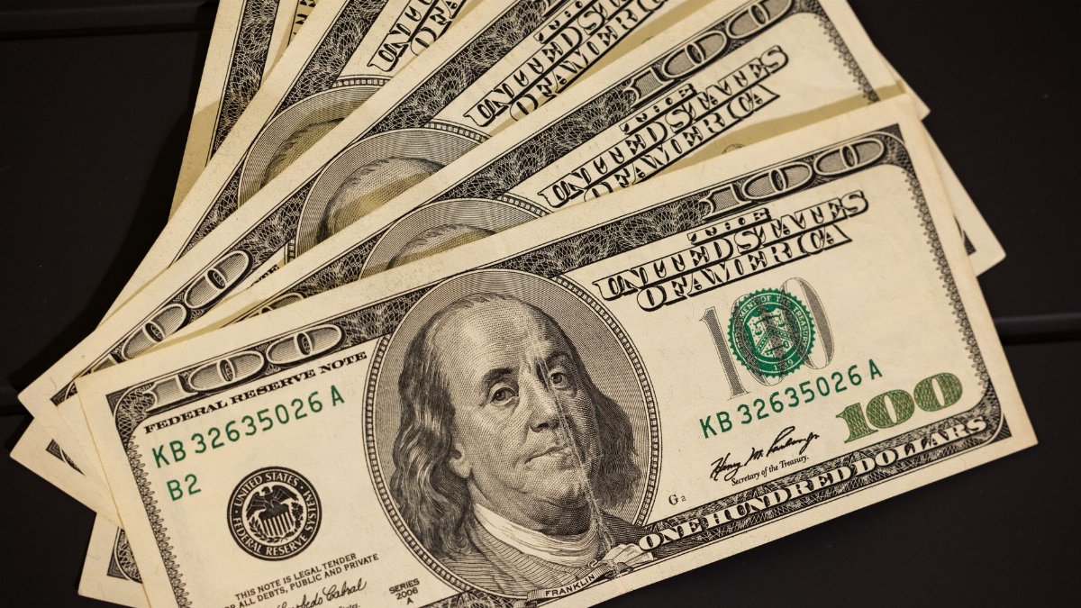 Close-up of US hundred dollar bills fanned out on a black surface for financial themes