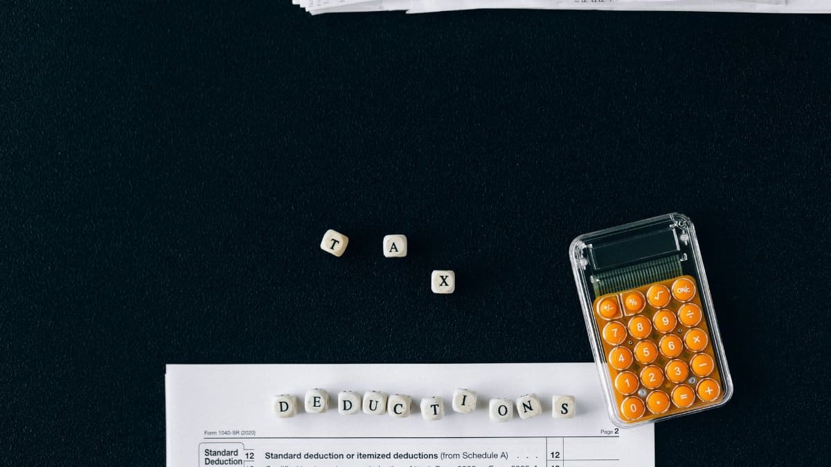 Top-down view of tax deduction items on a black background with a calculator and forms, emphasizing financial planning.