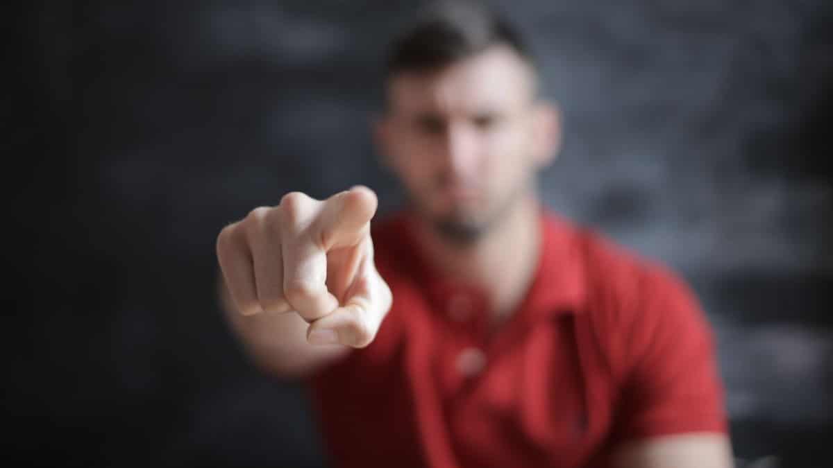 Blurred man pointing forward, emphasizing index finger close-up.