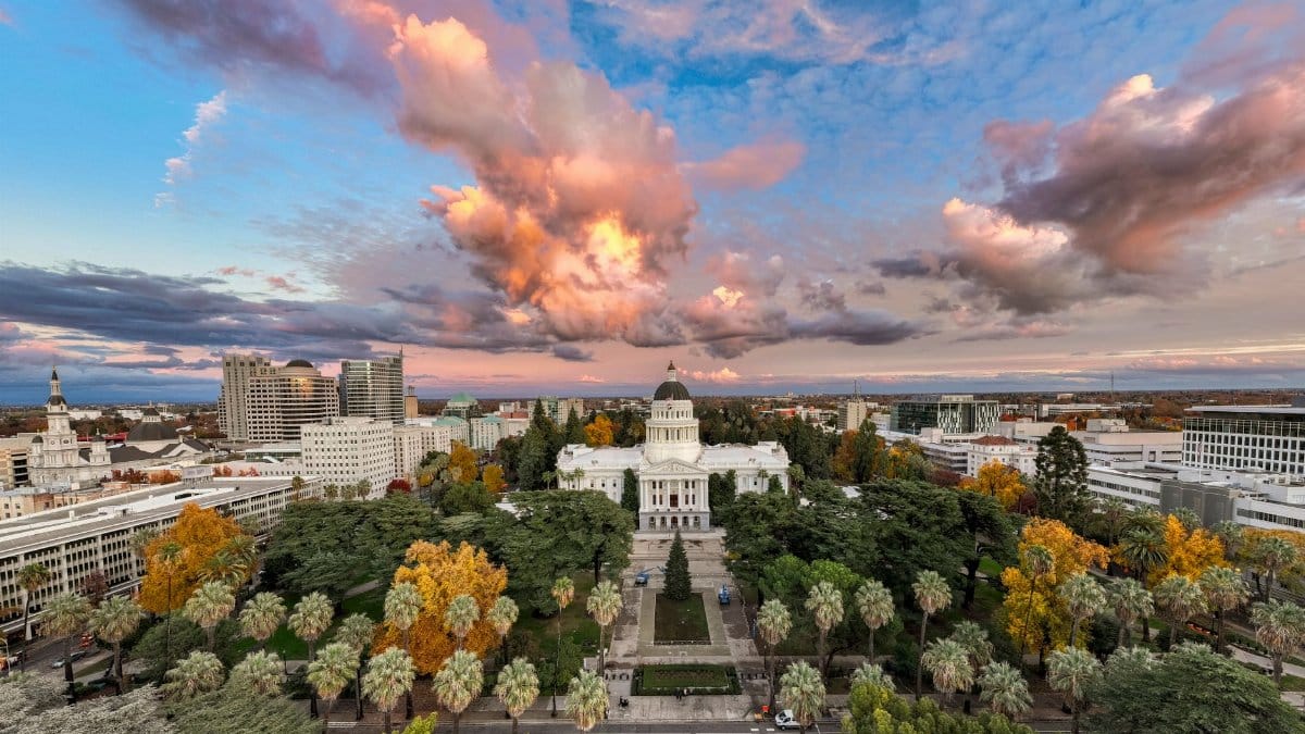 Dramatic sunset over Sacramento's California State Capitol, showcasing autumn colors and a vibrant sky.
