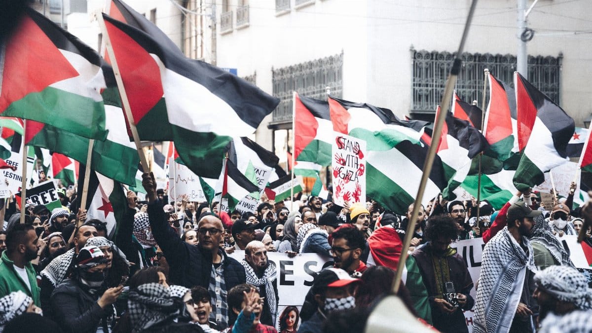 Protesters holding Palestinian flags in a demonstration outdoors, displaying unity and political activism.