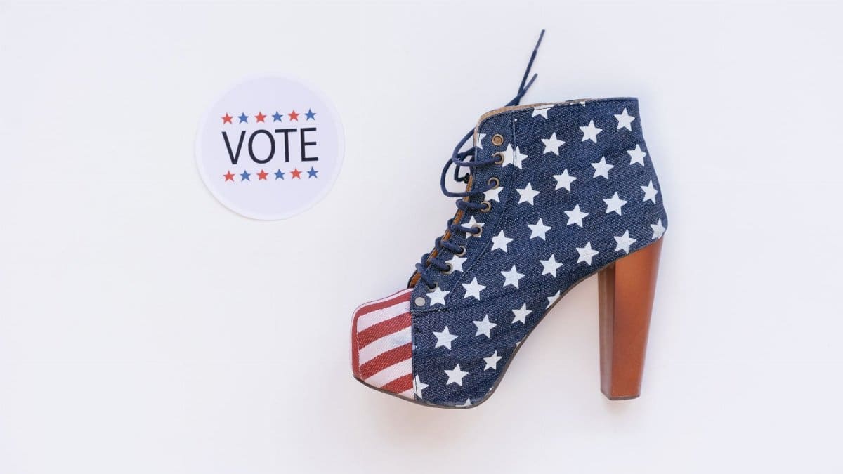 High heel with American flag design beside a voting sticker on white background.