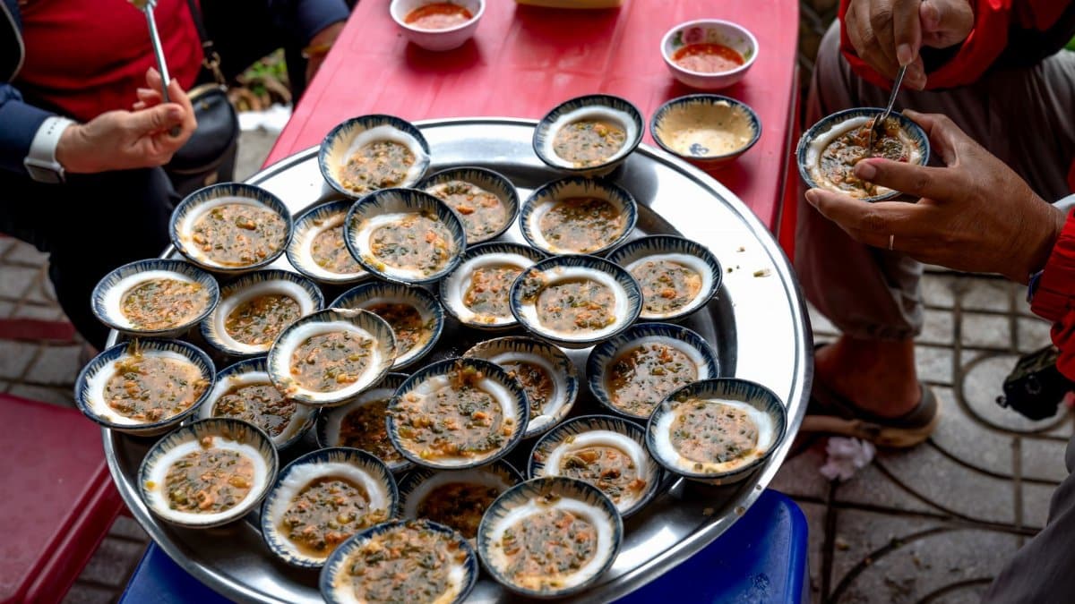 Street food with multiple small dishes on a tray, served outdoors with vibrant sauces.
