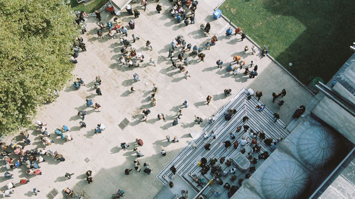 An aerial shot capturing a bustling city plaza filled with diverse crowds on a sunny day.