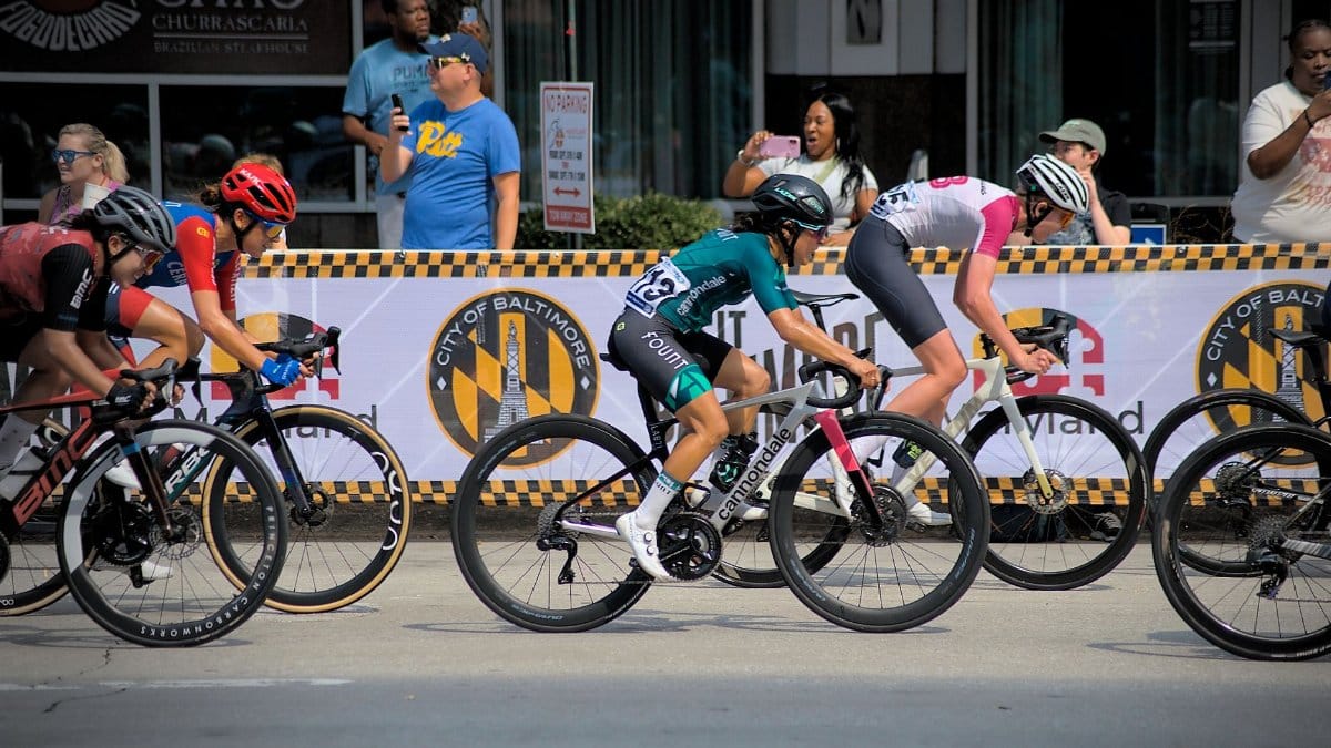 Cyclists racing in Baltimore, Maryland event. Energetic and competitive scene with city backdrop.