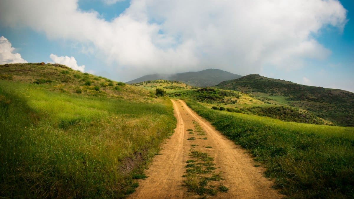 A picturesque dirt road winds through the green hills of Huamantanga, Lima, Peru.