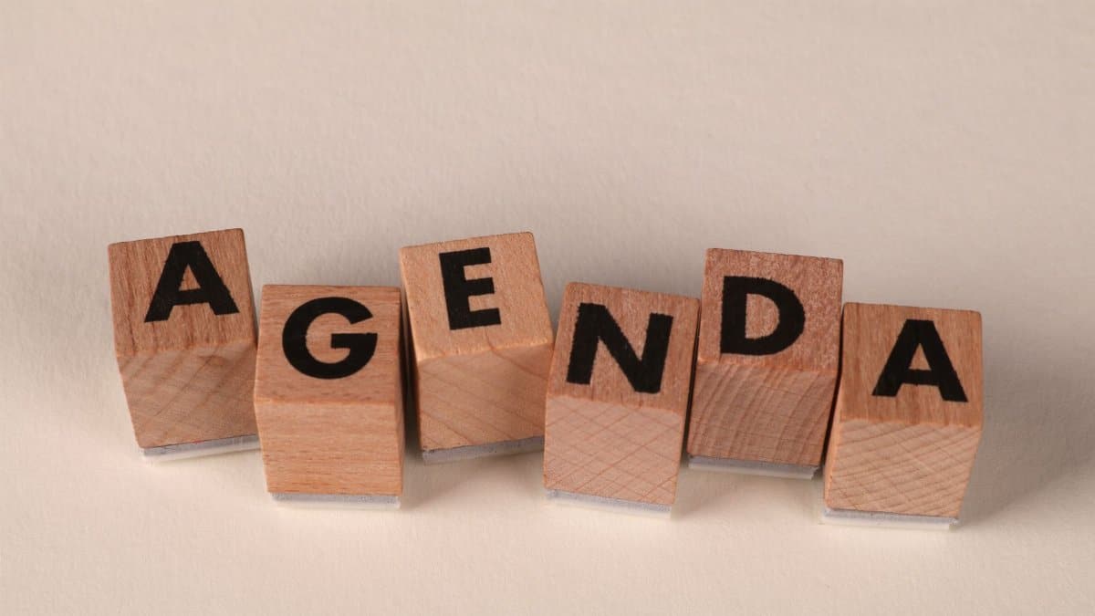 Close-up of wooden blocks spelling 'AGENDA' on a soft neutral background.