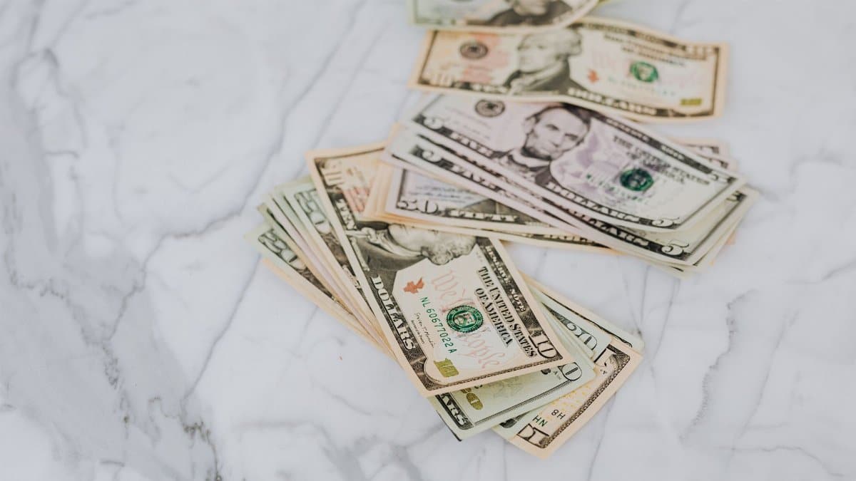 A stack of US dollar bills spread on a marble surface, representing wealth and finance.