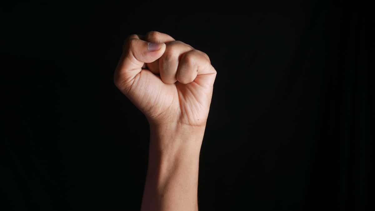 A raised fist against a dark background symbolizing strength, determination, and solidarity.