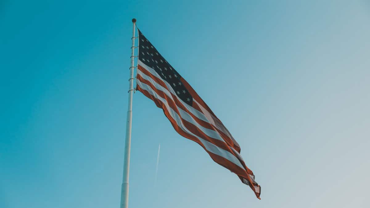 Low angle view of the American flag waving on a windy day against a clear blue sky.