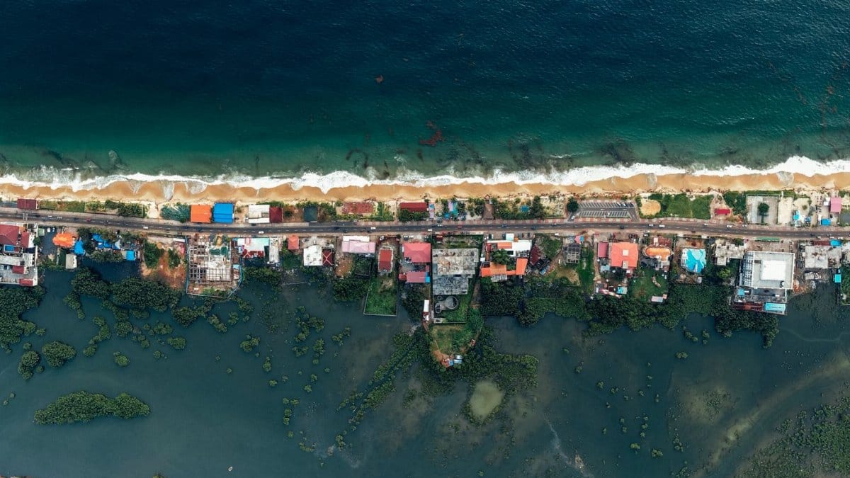 Panoramic aerial shot of a coastal village with ocean and lush greenery.