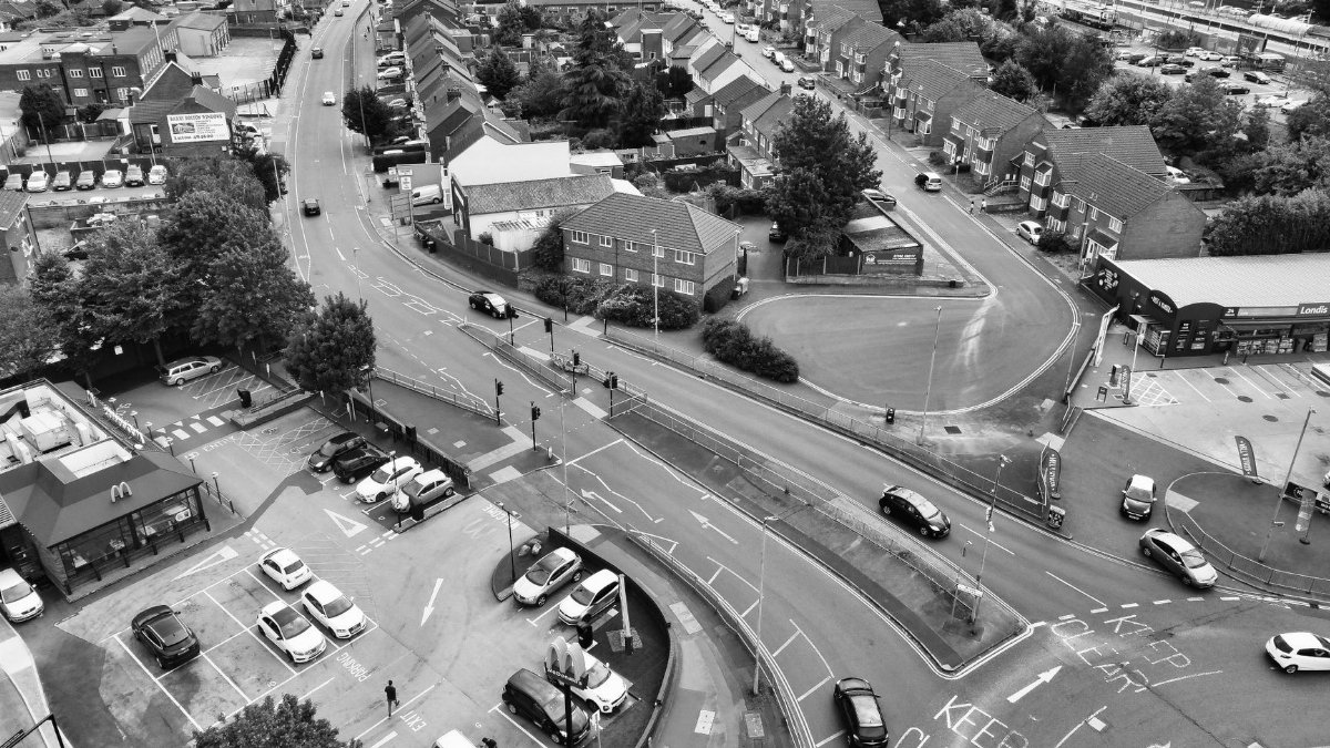 Aerial black and white view of urban streets and traffic in an English town.