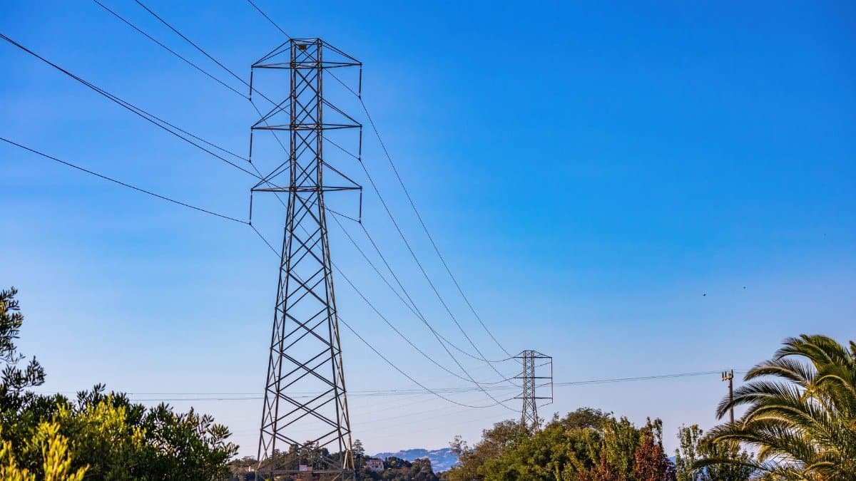 High voltage transmission towers against a clear blue sky, symbolizing modern energy infrastructure.